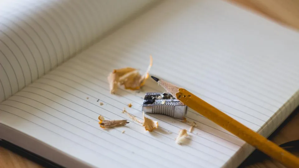 Cuaderno abierto con un lápiz recién afilado sobre una mesa de madera